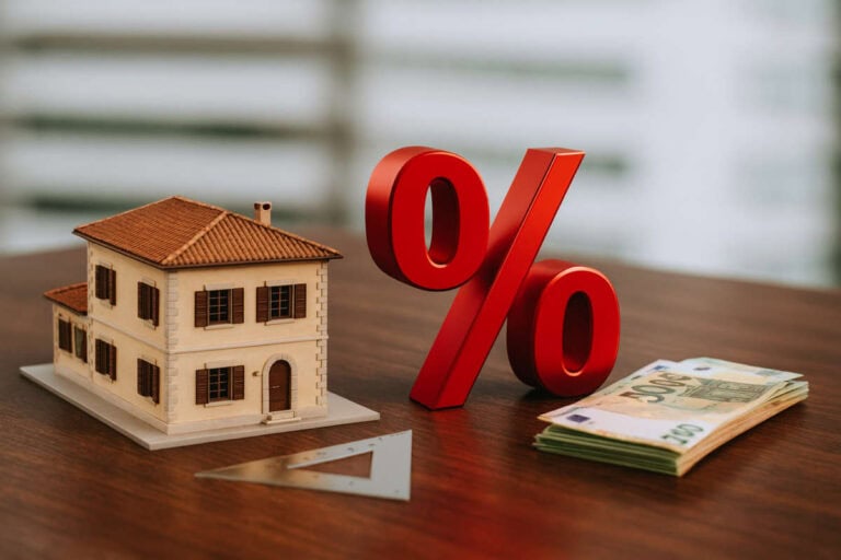 Modellino di casa con simbolo percentuale e banconote euro, concetto di Bonus casa 2026