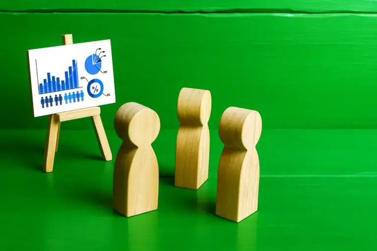 mese educazione finanziaria con figure in legno davanti a un grafico su cavalletto